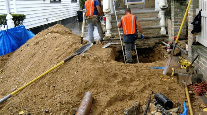 Contractors performing foundation protection and exterior drainage excavation near residential home steps in Buffalo, NY