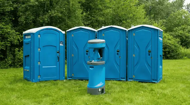 Four blue portable toilets and a matching hand washing station on grass near trees, a common sight at local outdoor events in Buffalo, NY